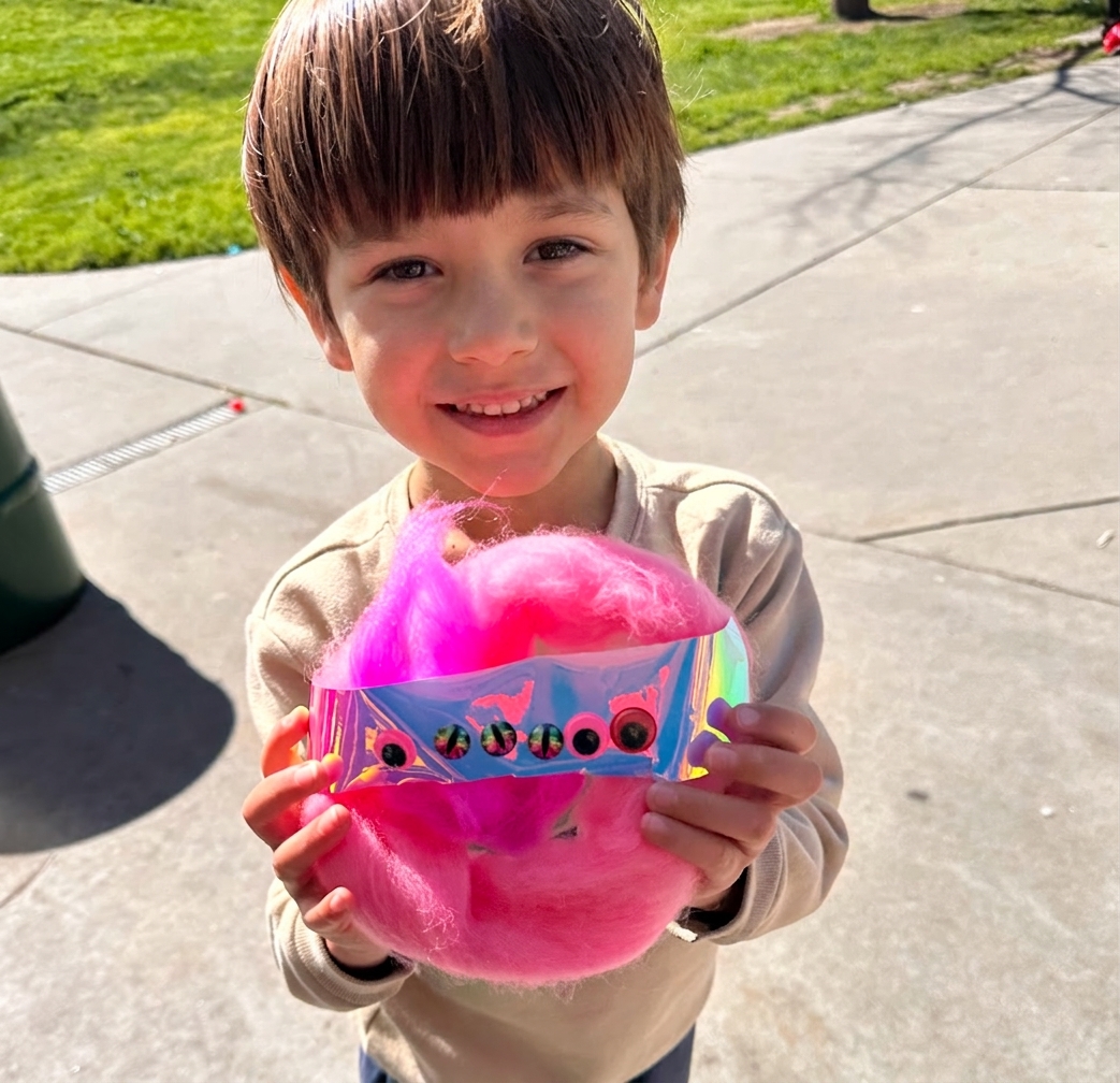 A child holding up their finished pink critter creation