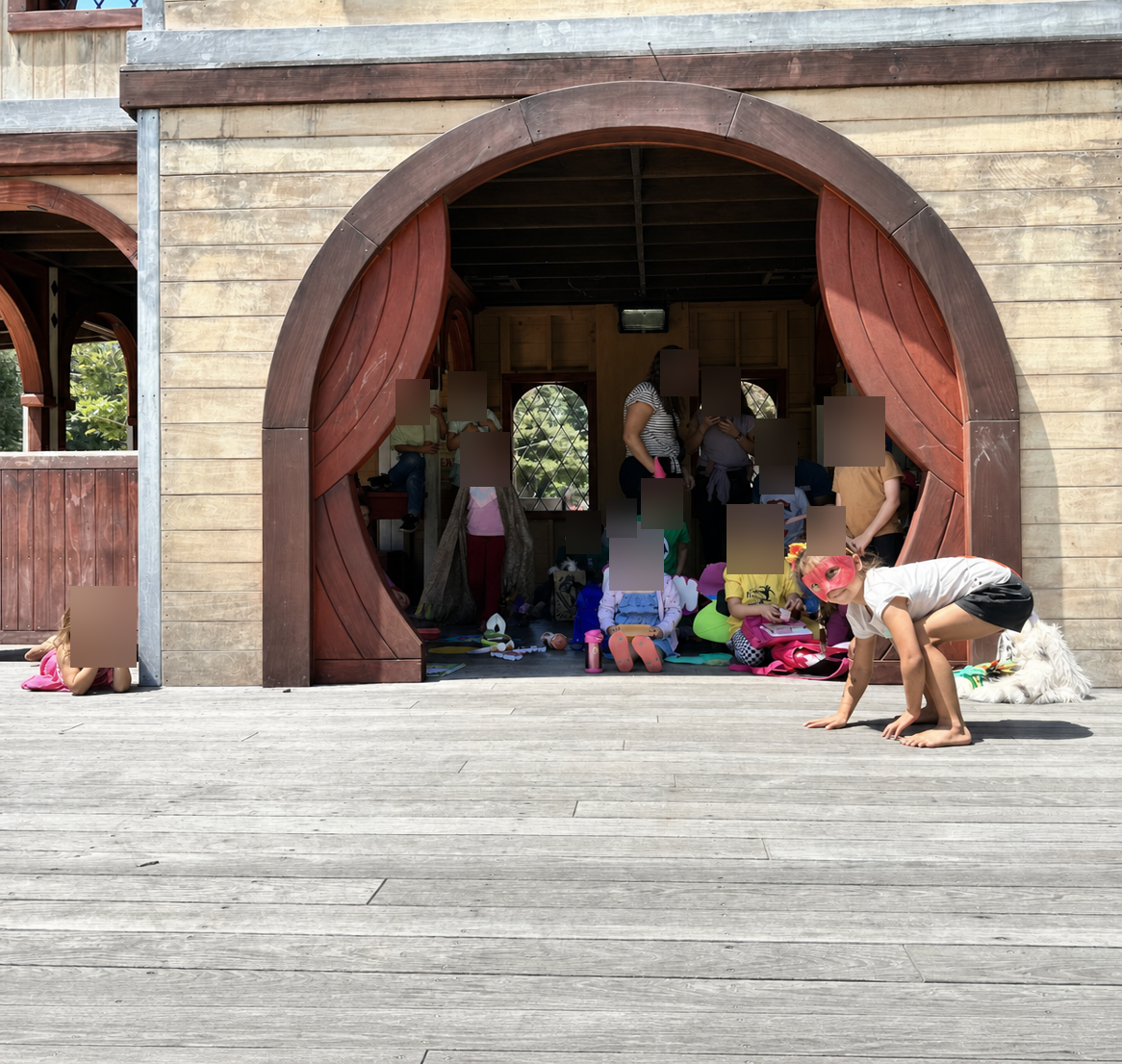 Children testing structural stability of handmade straw and stick houses against the wind