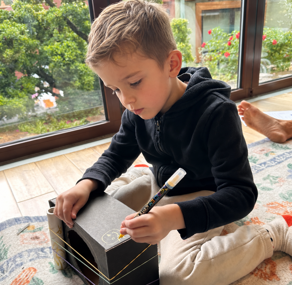 A child carefully adjusting copper chime pipes on a wooden frame