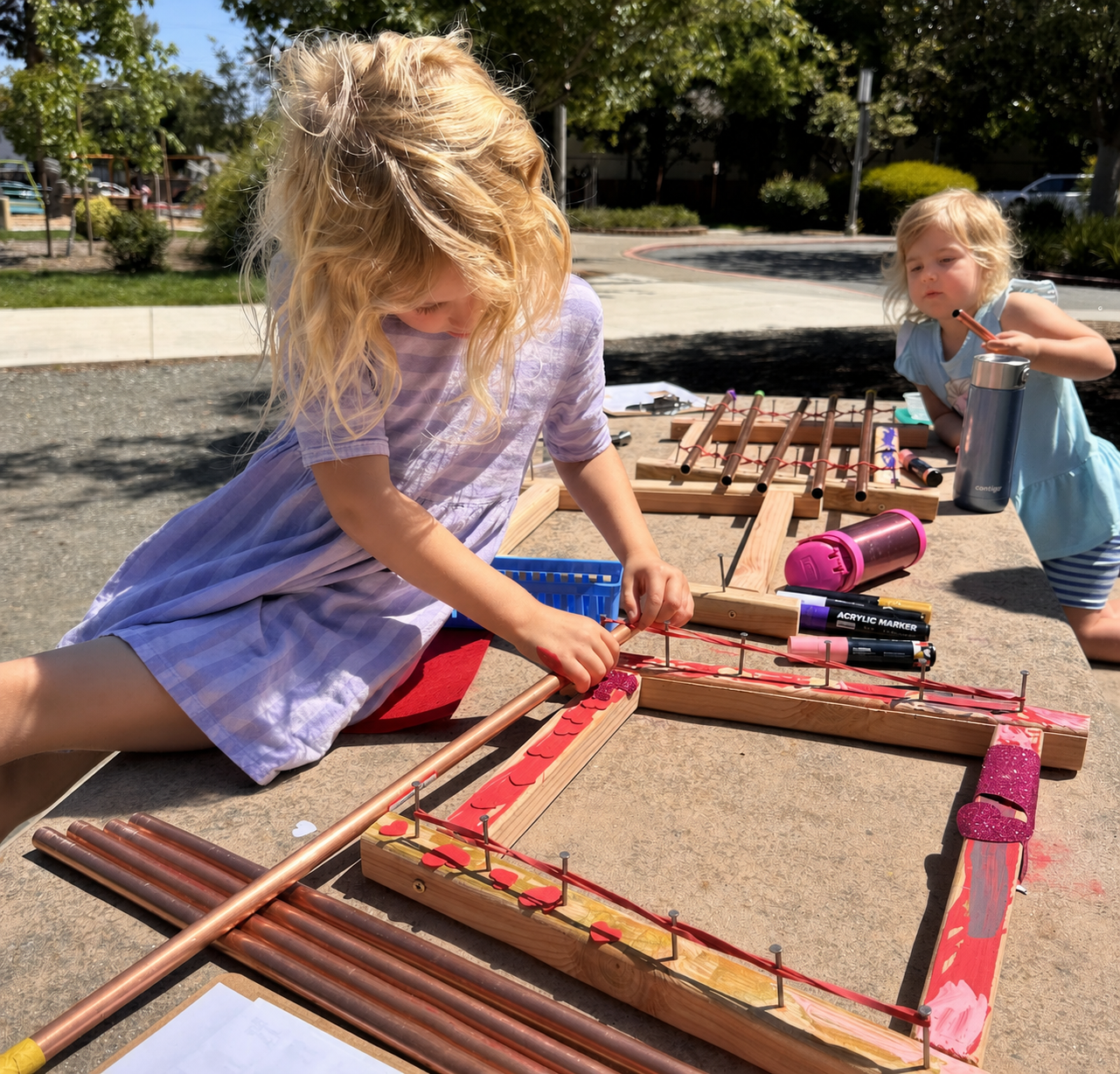 A child carefully painting details onto a wooden fairy peg doll with an acrylic paint pen.
