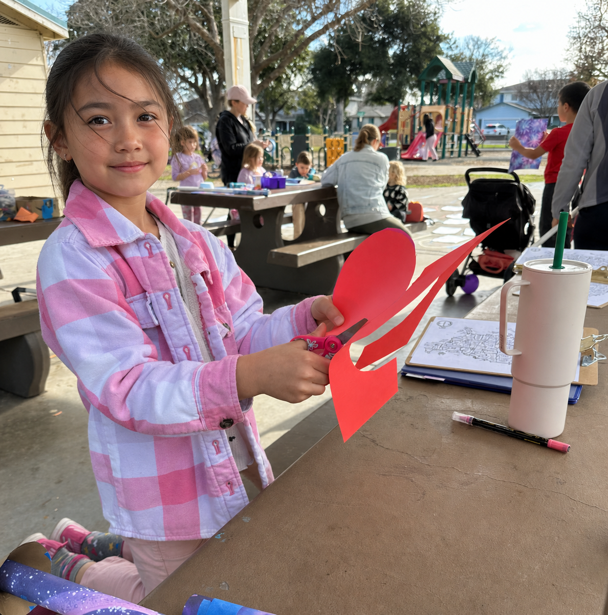 A child stomps on a soda bottle launcher, sending a paper rocket soaring across a massive colorful chalk map of the United States drawn on the pavement.