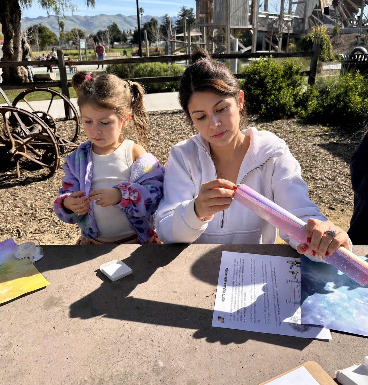 Two children collaborating, one holding a telescope and the other taking notes.