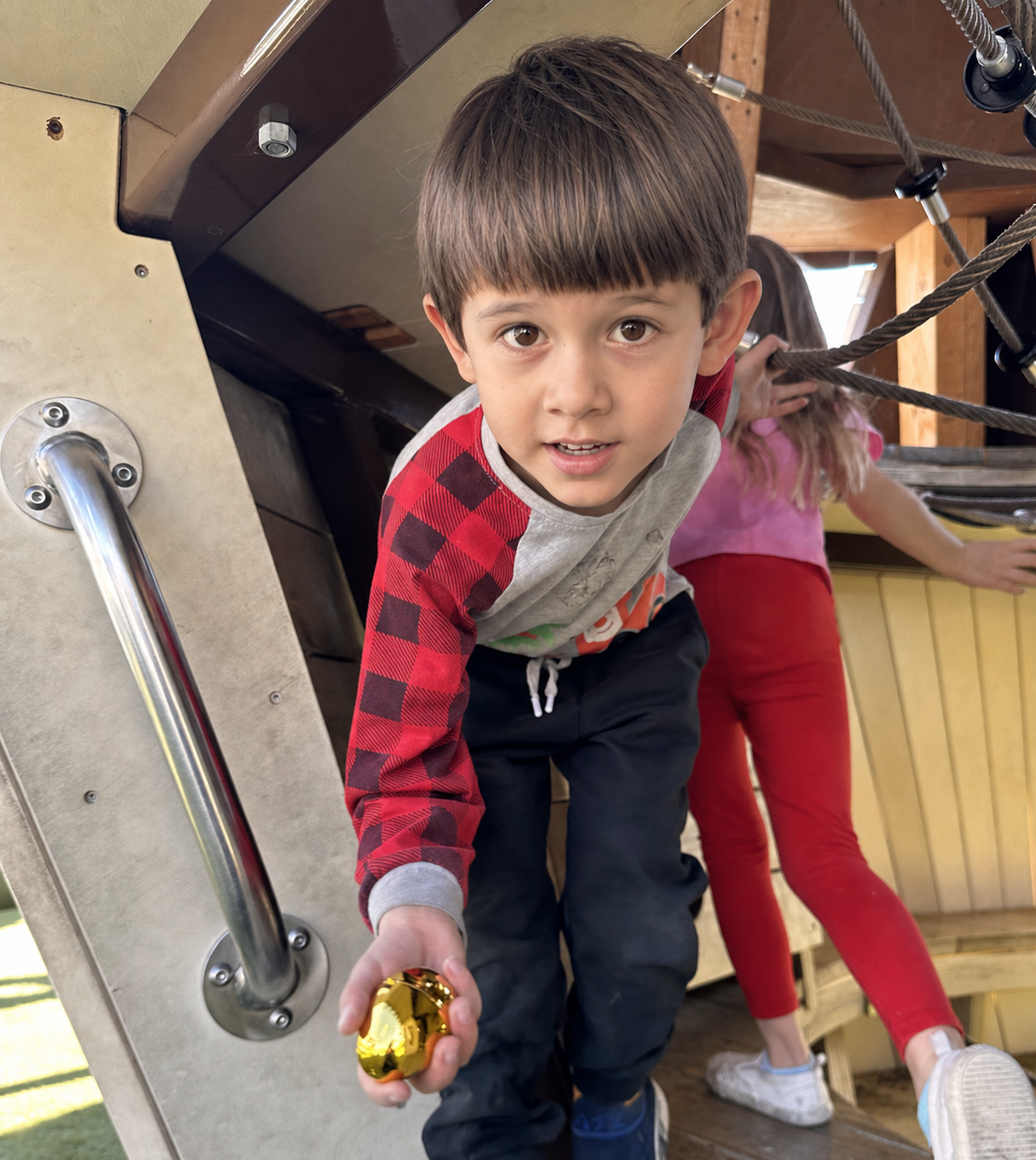 A child proudly holding a golden egg containing a golden bee.
